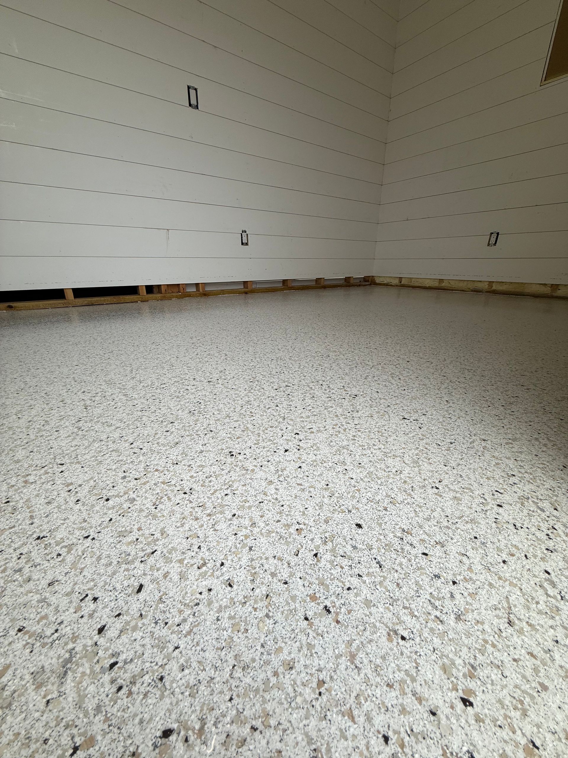 Empty carpeted room with white walls and exposed baseboards under construction