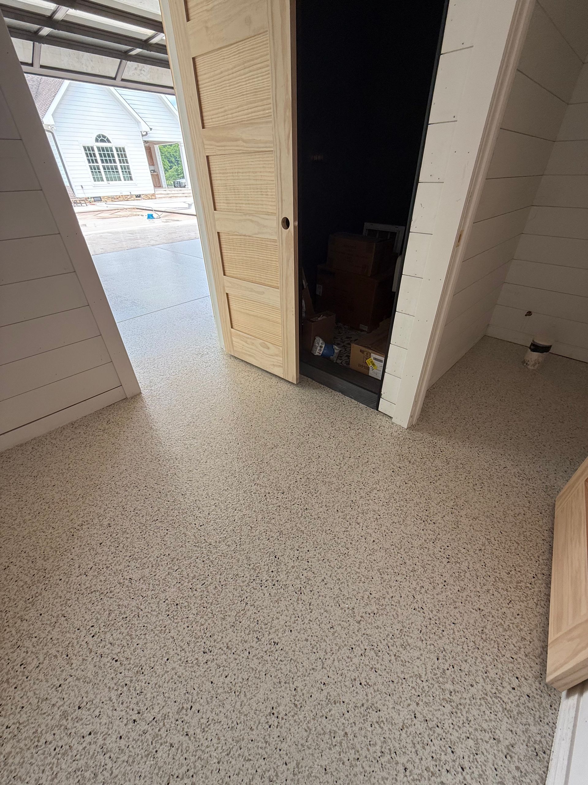 Open door in a tiled room, showing a dark interior and bright outside light.