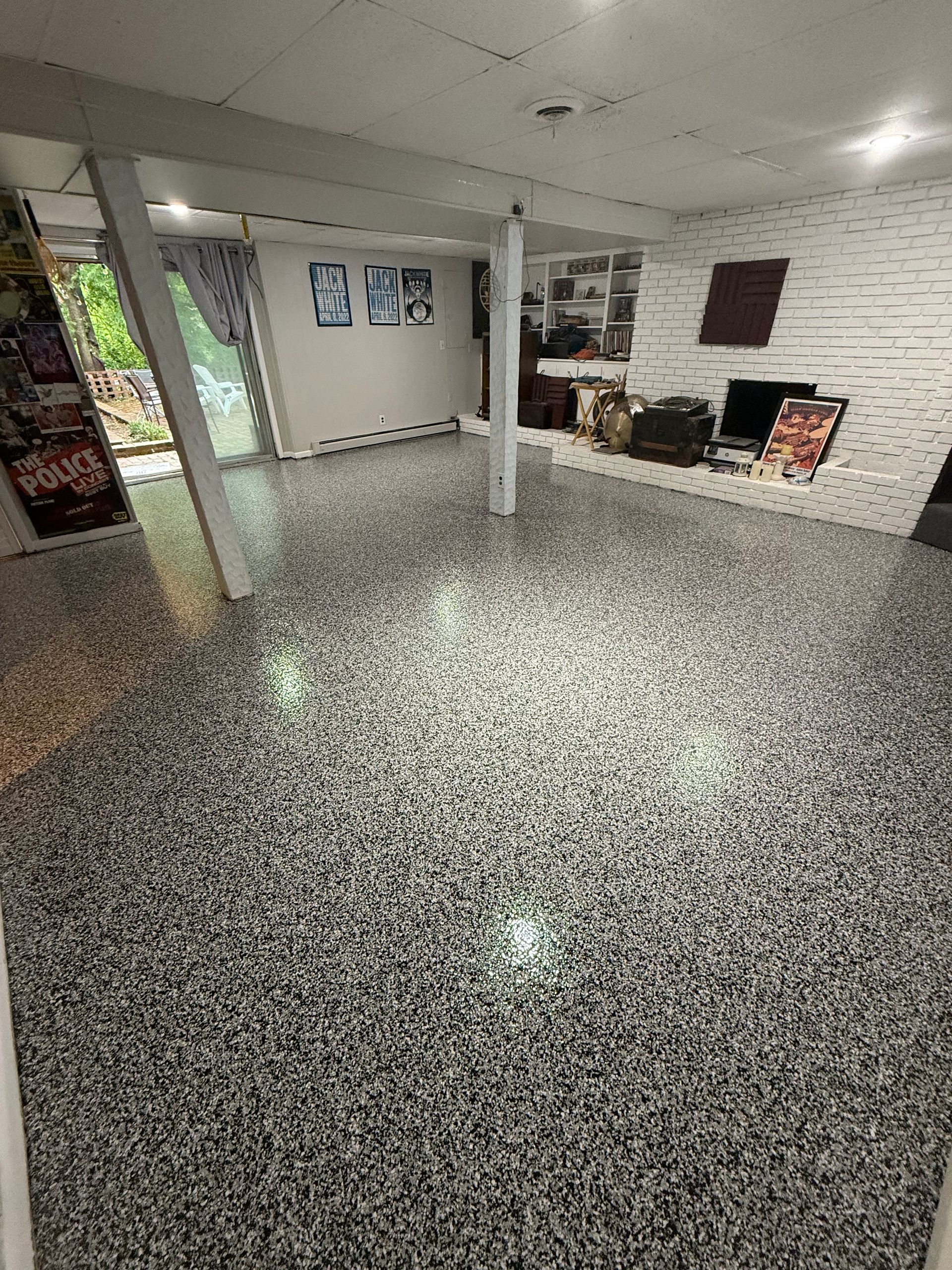 Empty indoor lobby with gray speckled floor, white columns, and a fireplace on the right.