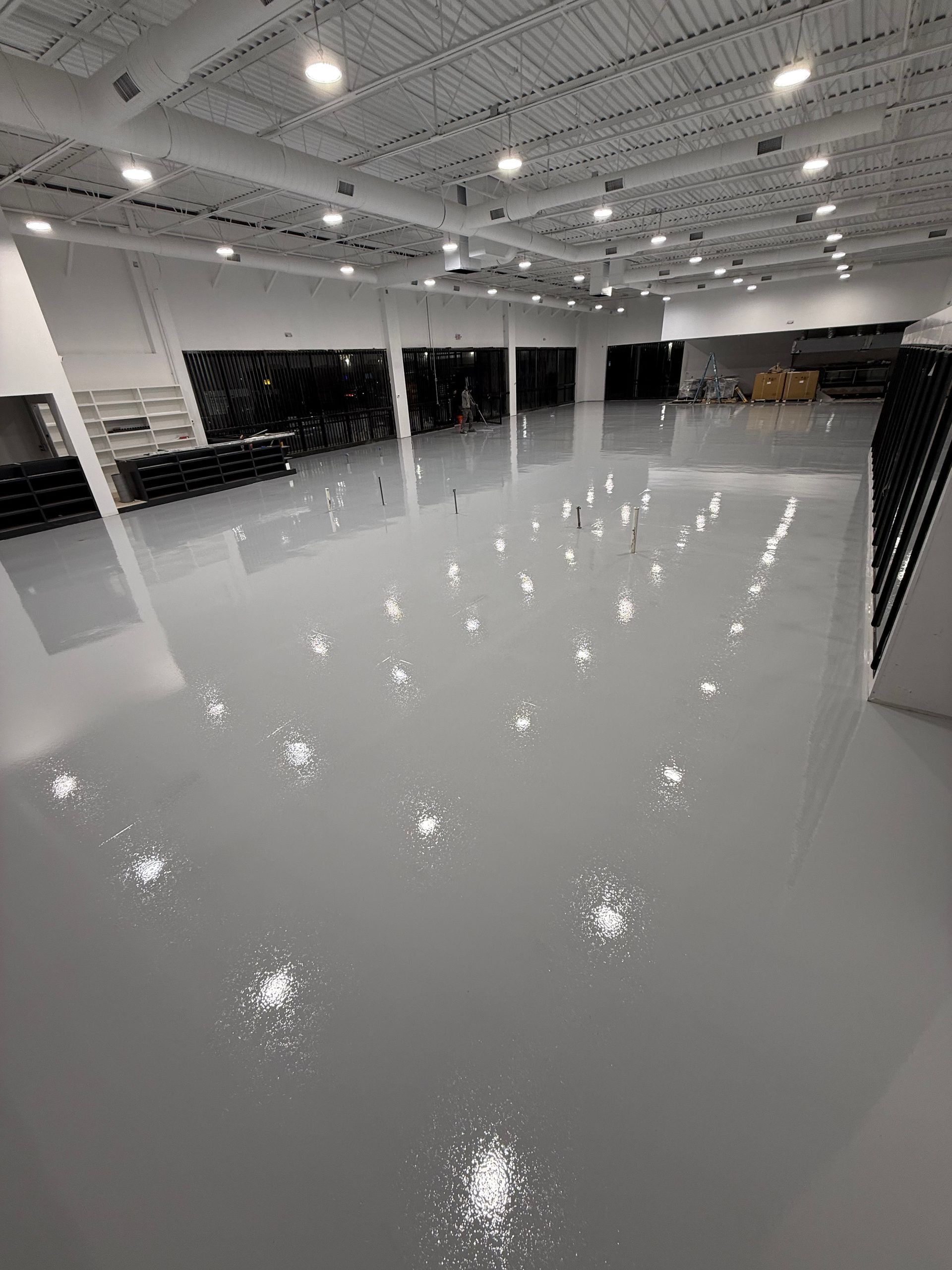 Empty glossy showroom floor under bright ceiling lights, with large windows and a wide open interior.
