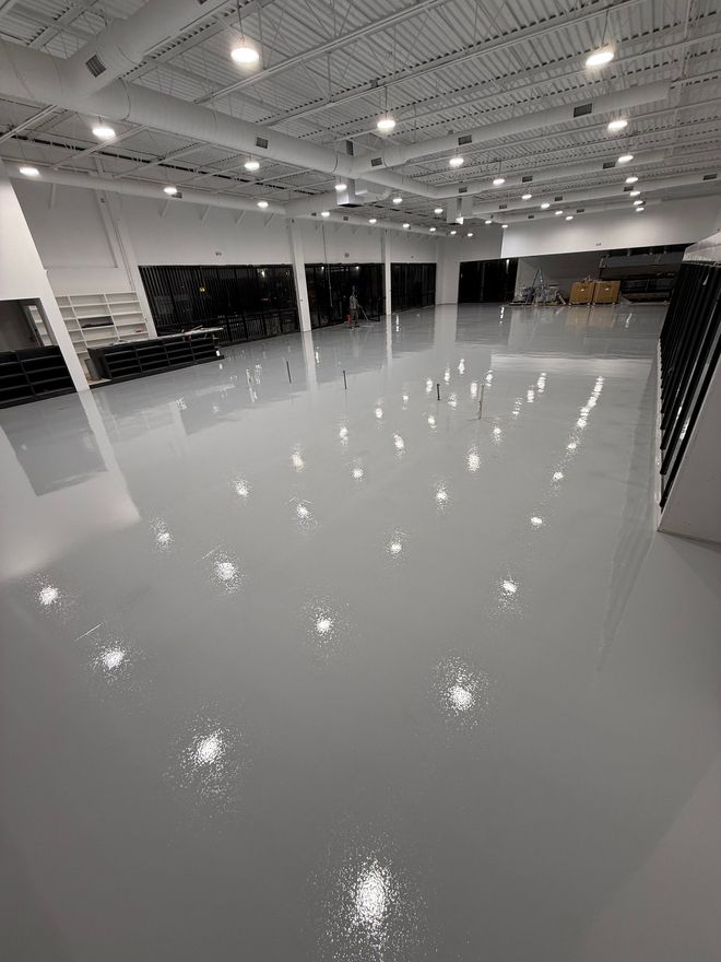 Empty glossy showroom floor under bright ceiling lights, with large windows and a wide open interior.