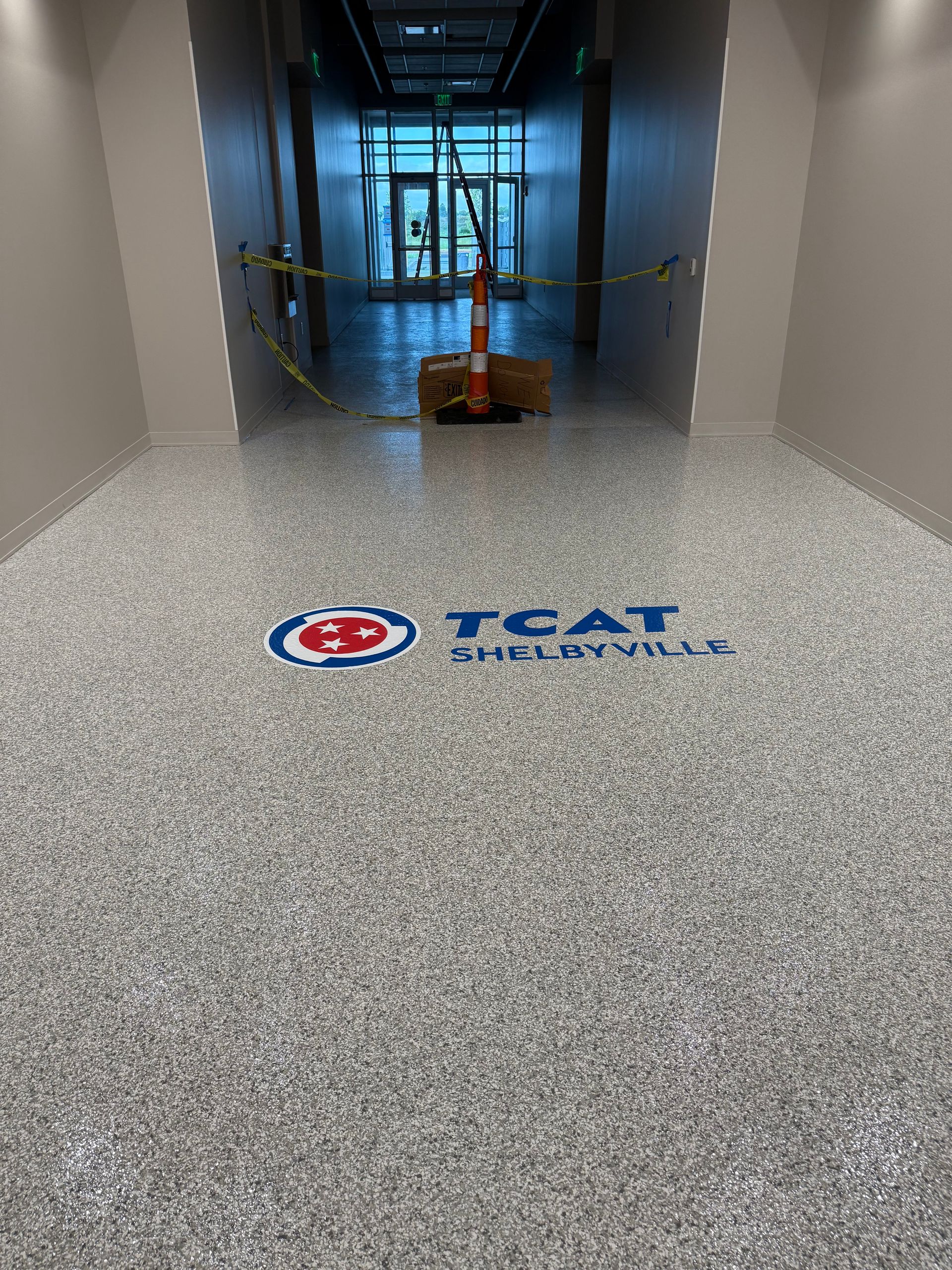 TSG logo on a speckled floor in a hallway with caution tape and a blocked entrance ahead