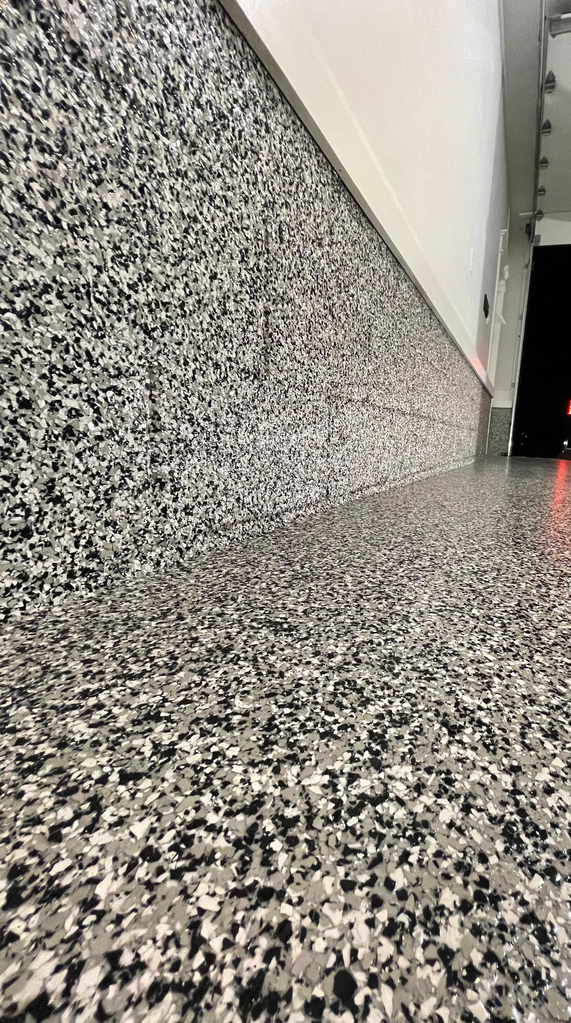 Low-angle view of a speckled terrazzo floor beside a white wall in a hallway