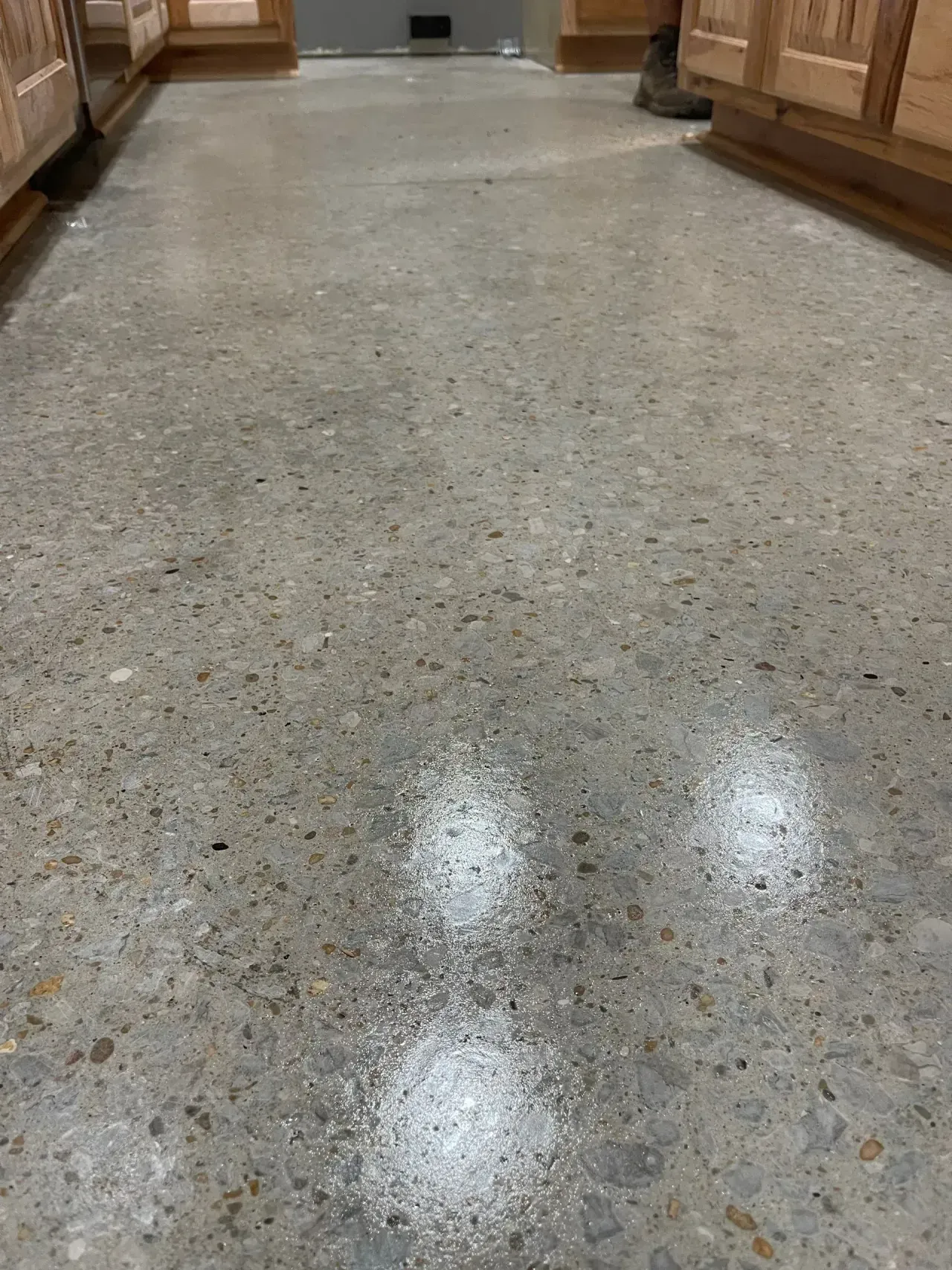 Polished speckled terrazzo hallway floor with wooden benches or counters along both sides
