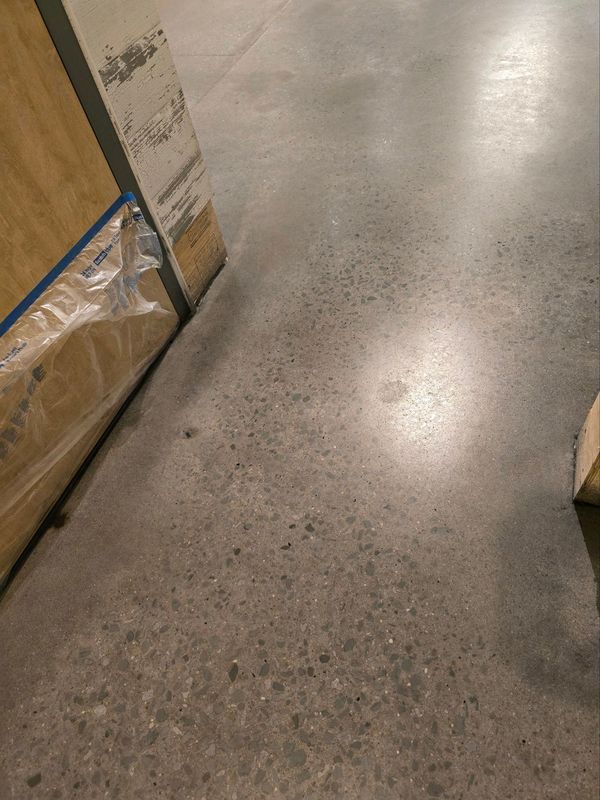 Warehouse aisle with concrete floor and stacked cardboard boxes along the left side.