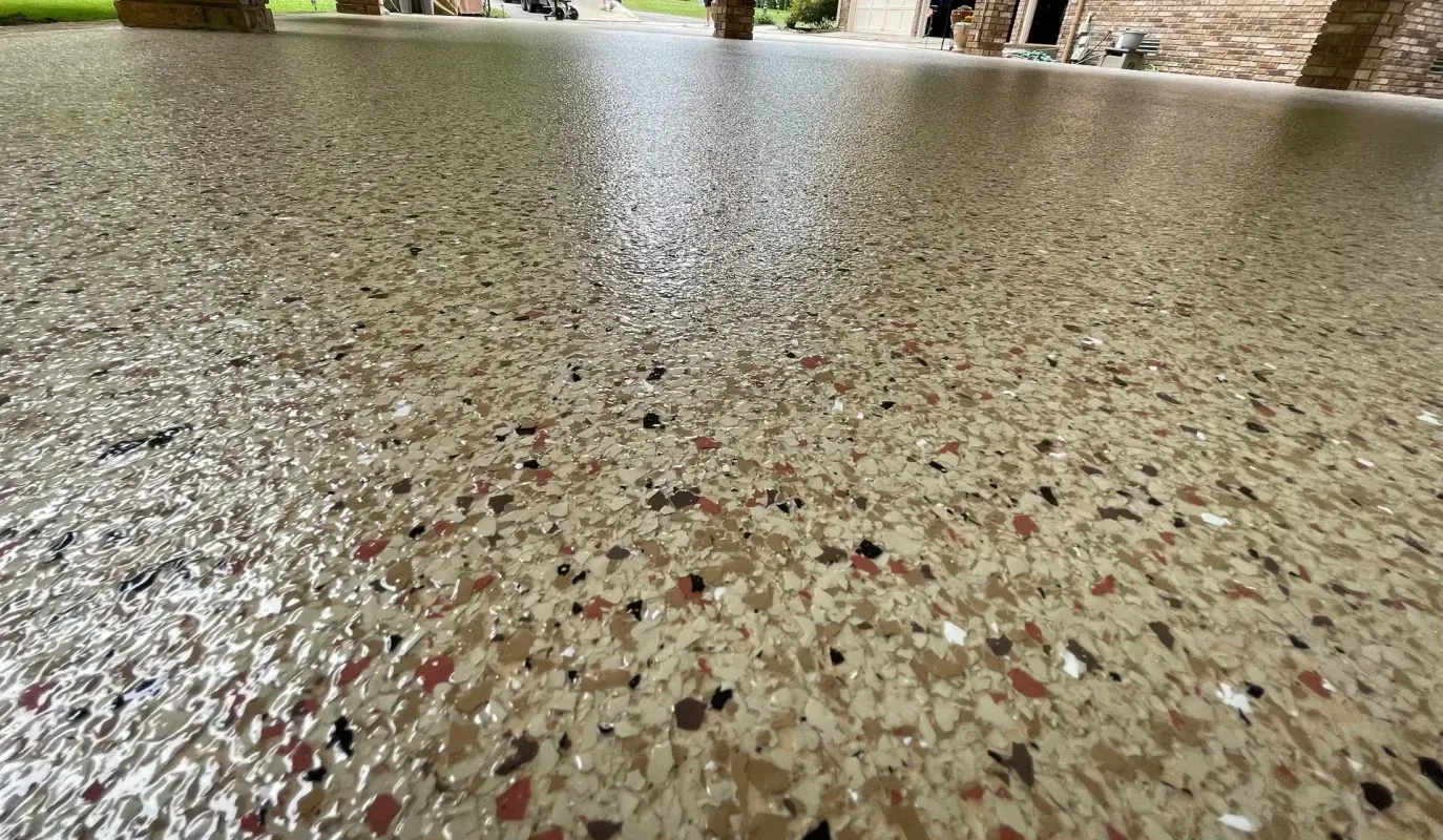 Close-up of a speckled terrazzo floor with a glossy surface and blurred plants in the background