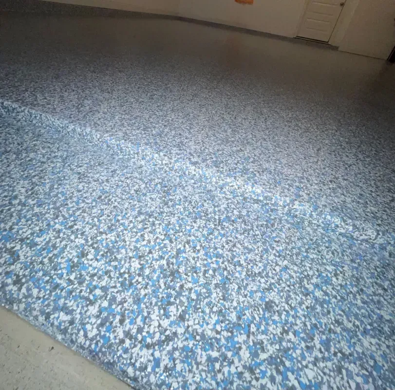 Blue and white speckled carpet floor in a room with baseboard and door in the background