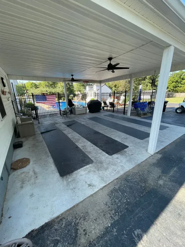 Covered patio with ceiling fans, black rugs, and outdoor seating overlooking a yard and pool