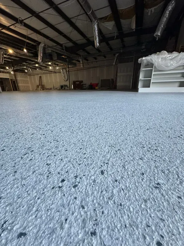 Empty warehouse interior with rough concrete floor and exposed ceiling beams