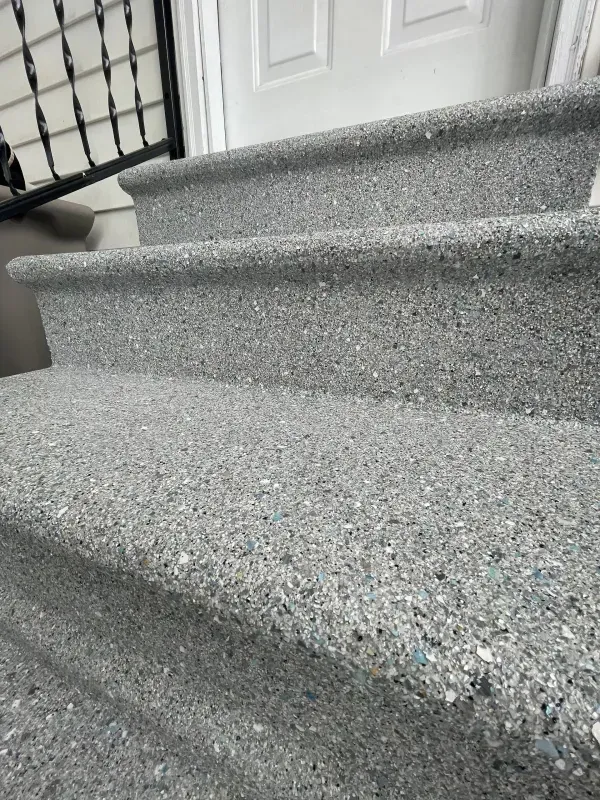 Carpeted stairs with gray textured steps and a white door at the top