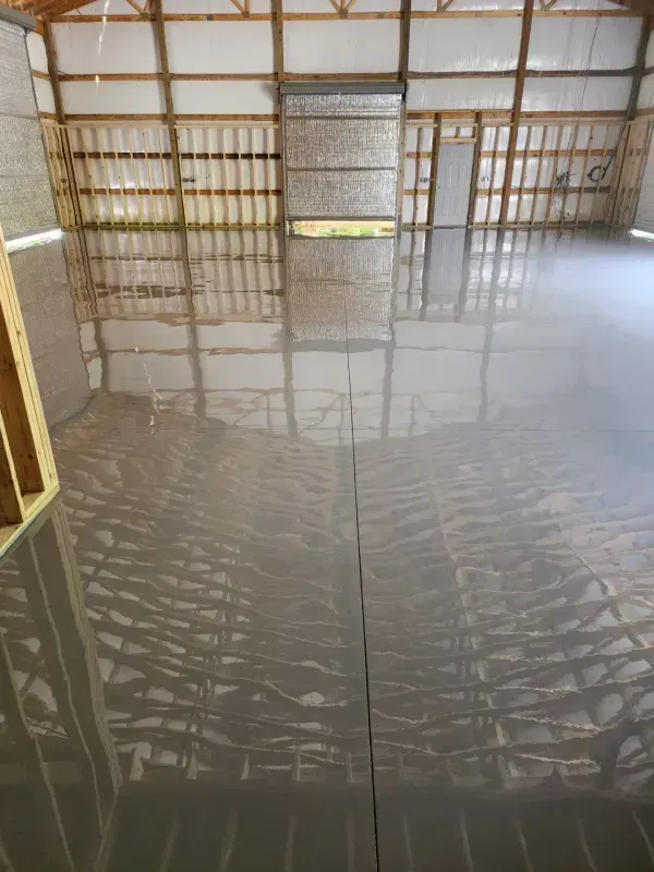 Empty indoor room with glossy concrete floor and unfinished wooden framing walls.