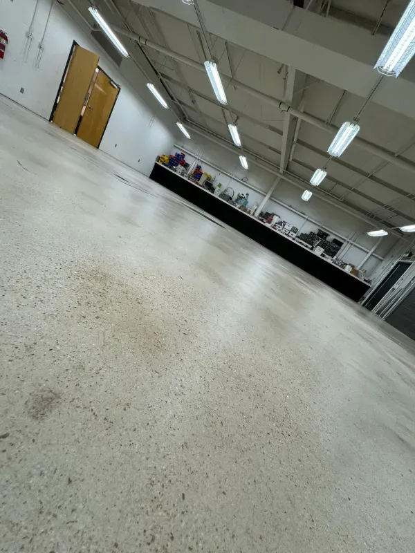 Low-angle view of an empty indoor warehouse with fluorescent lights and a long worktable