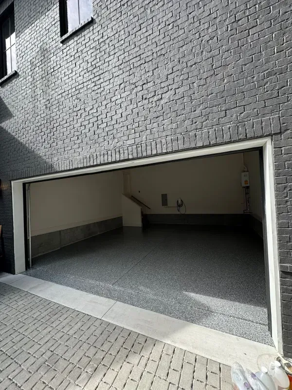 Empty residential garage with a gray brick exterior and paved driveway