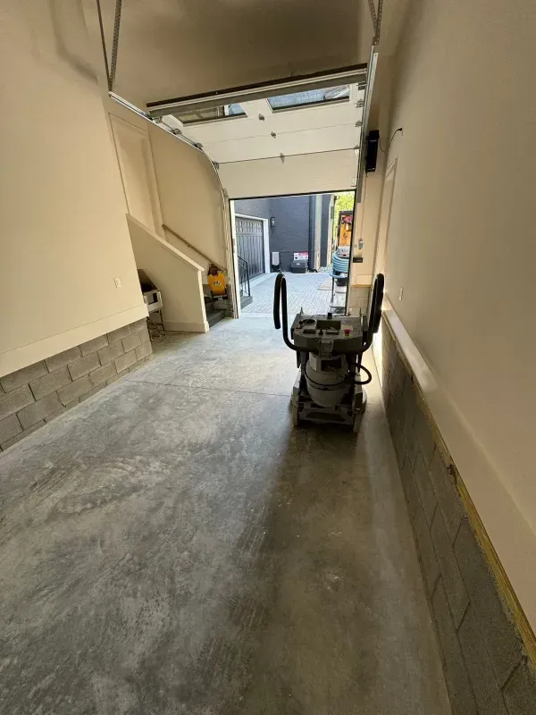 Narrow indoor corridor with a floor-cleaning machine and open doorway at the far end