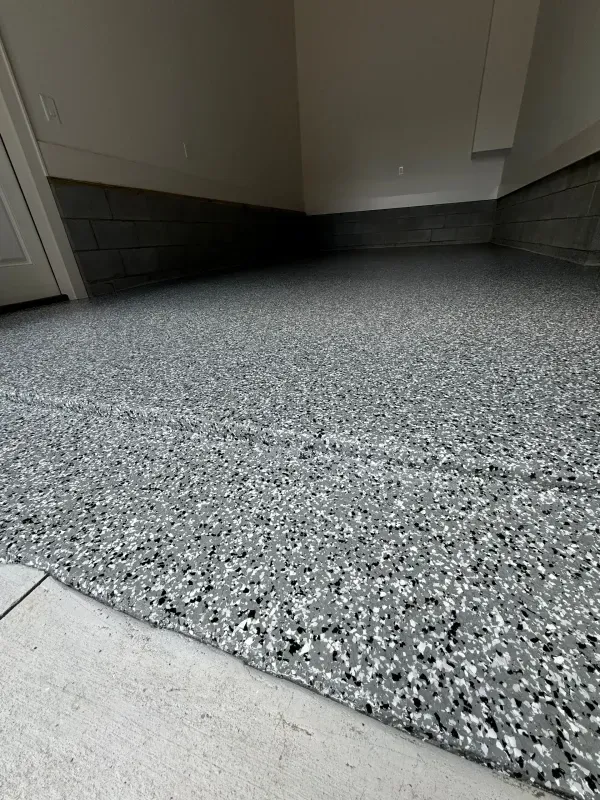 Textured gray floor at a doorway inside a room with white walls and dark baseboards