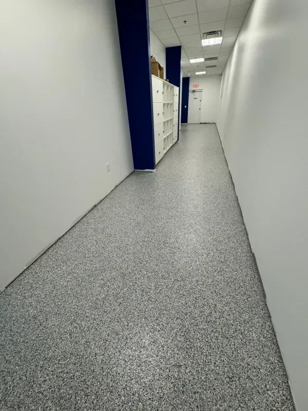 Empty office hallway with white walls, blue pillars, and gray carpet flooring