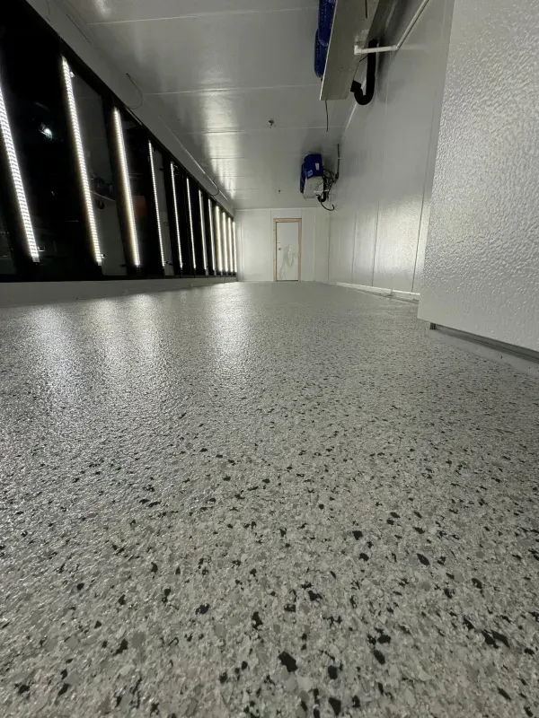 Low-angle view of a polished speckled floor in a bright hallway with black window panels and white walls