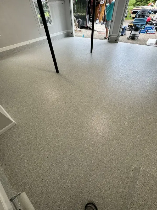 Speckled light-gray floor inside a storefront, looking out to the street through an open doorway