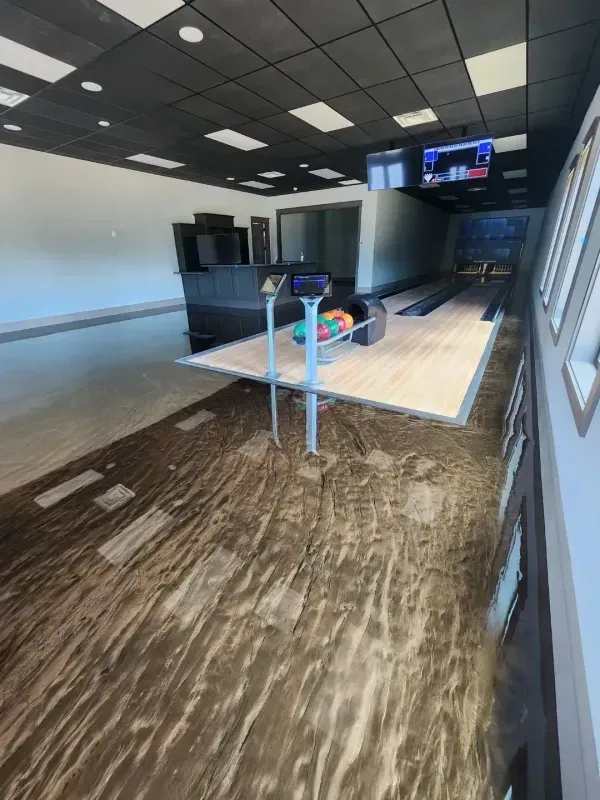 Empty modern lobby with stanchions, dark ceiling, wood floor, and a wall-mounted TV menu.