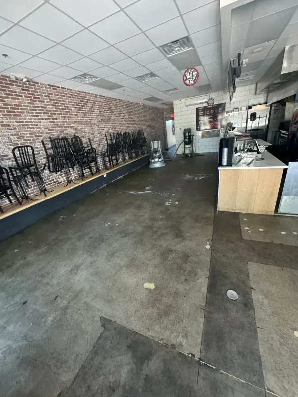 Empty restaurant interior with stacked chairs, brick walls, and a counter area