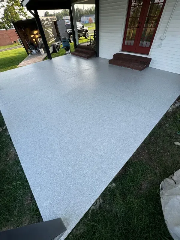 Freshly coated light gray porch floor beside white house siding and red door