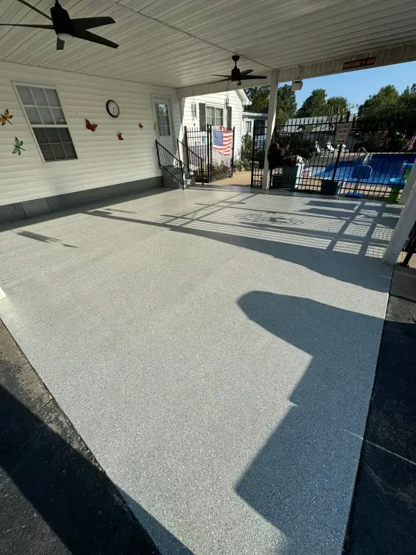 Covered patio with ceiling fan, empty concrete floor, and pool area in the background