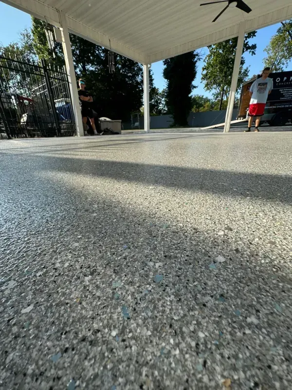 Low-angle view of a shaded patio floor with a person in a red shirt standing near the edge.