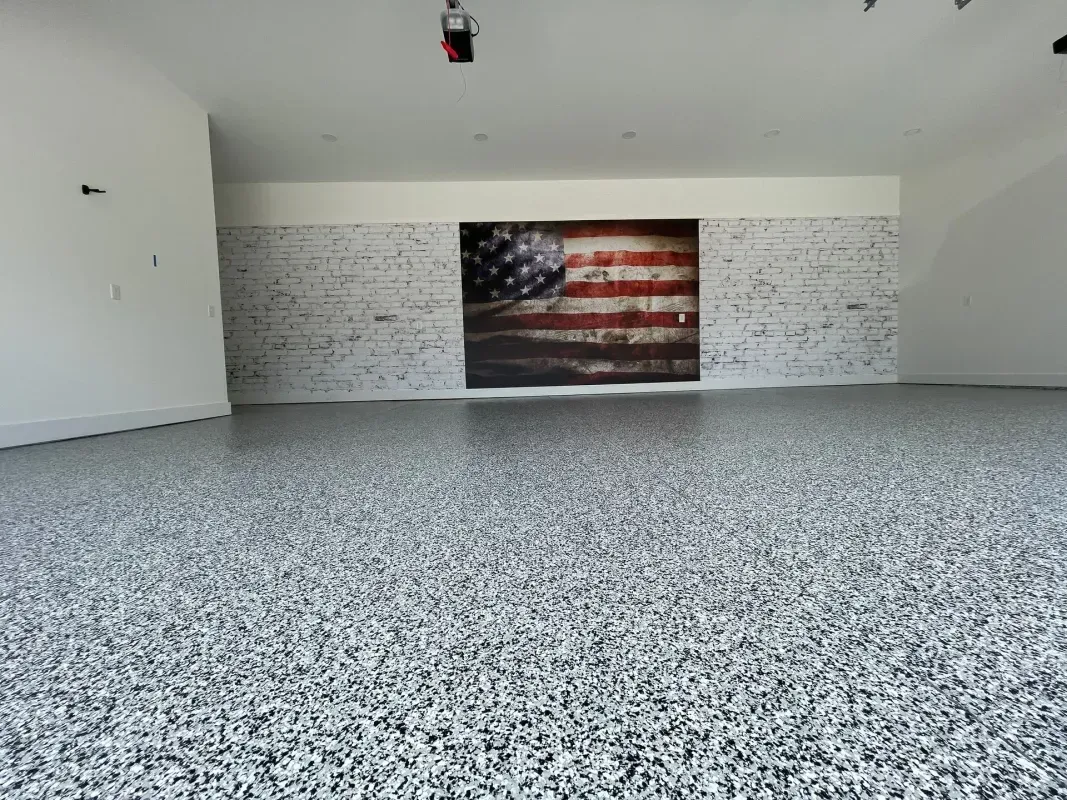 Empty garage with speckled epoxy floor and an American flag on the back wall.