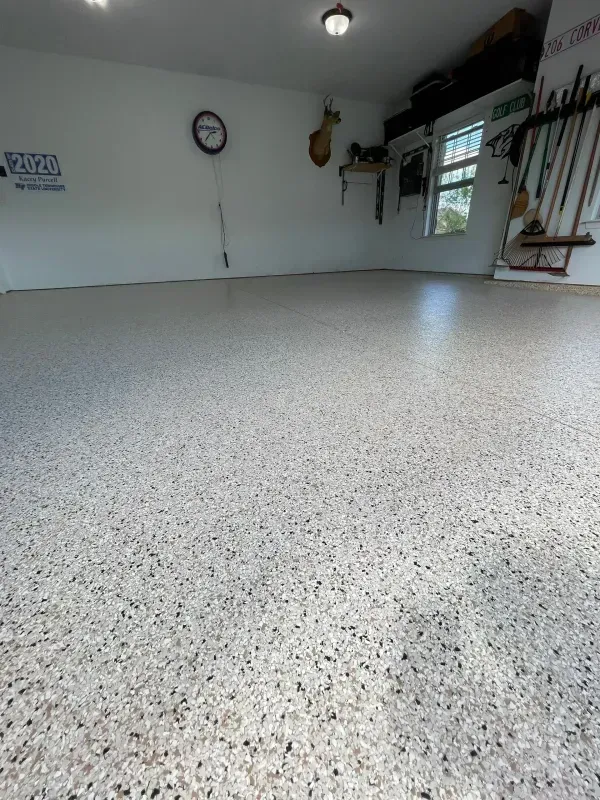 Empty speckled garage with white walls, a ceiling light, and a windowed door on the right.