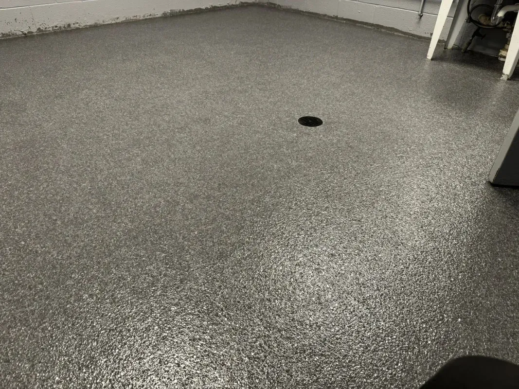 Gray speckled floor in a room with a small circular drain opening