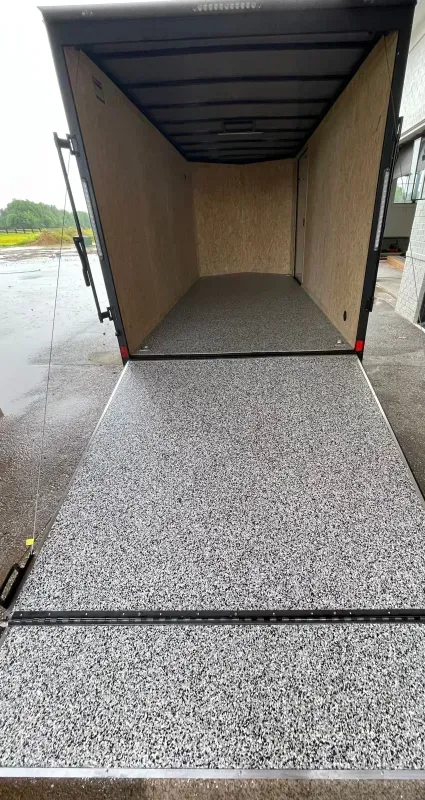 Open truck trailer with ramp and speckled floor on a wet driveway