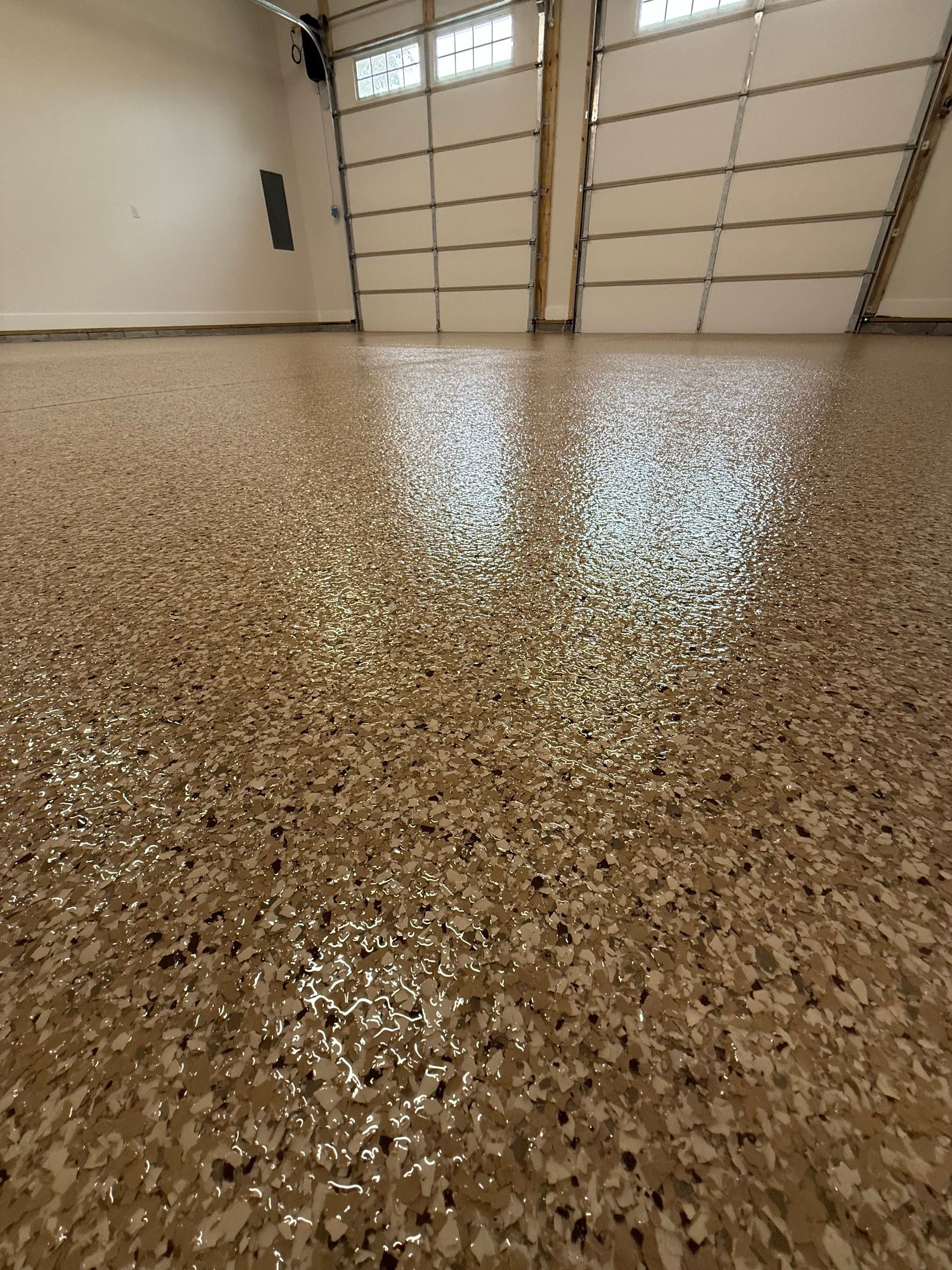 Shiny speckled garage floor with a closed segmented garage door in the background
