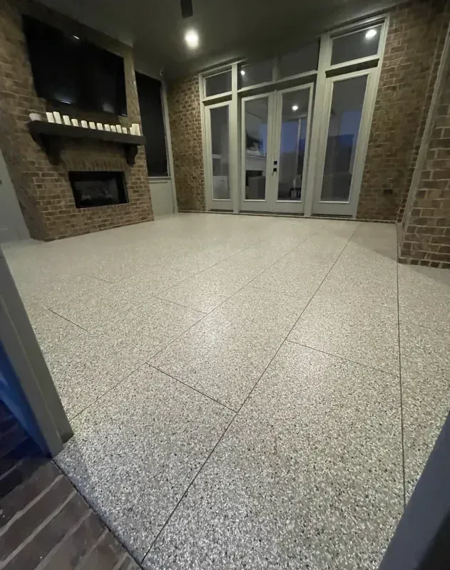 Empty brick entryway with glass doors and a speckled concrete floor at dusk