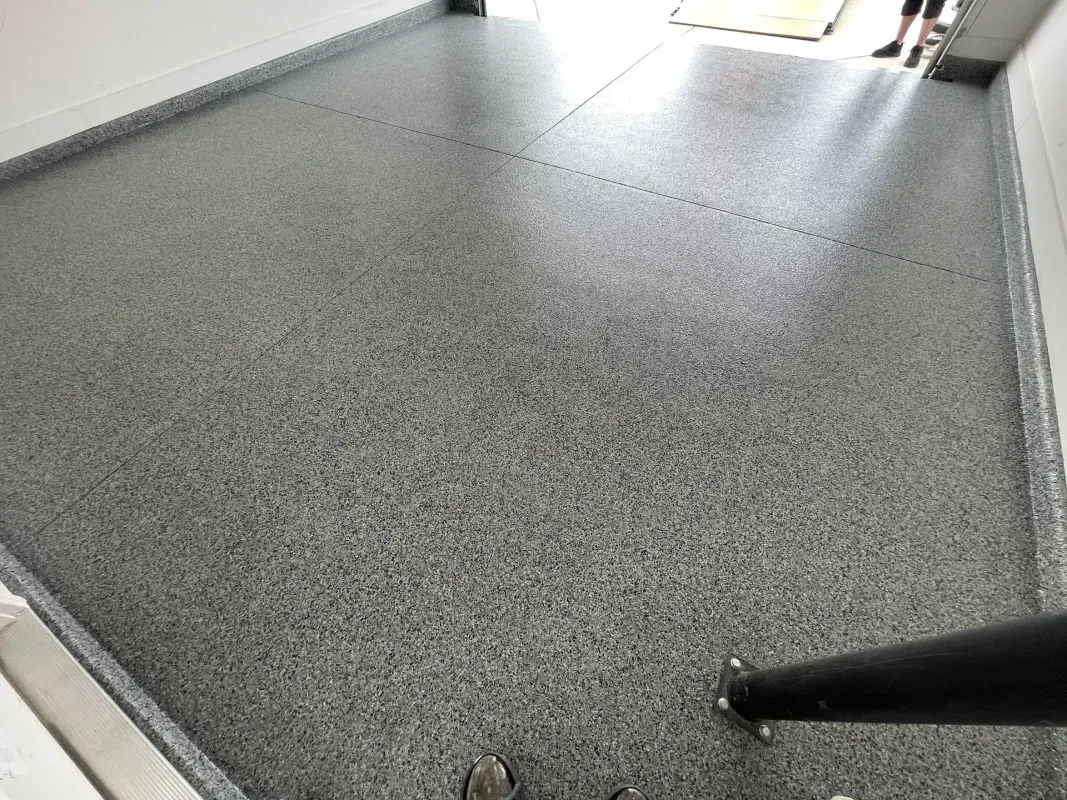 Gray speckled stair landing with a handrail and bright light at the top opening