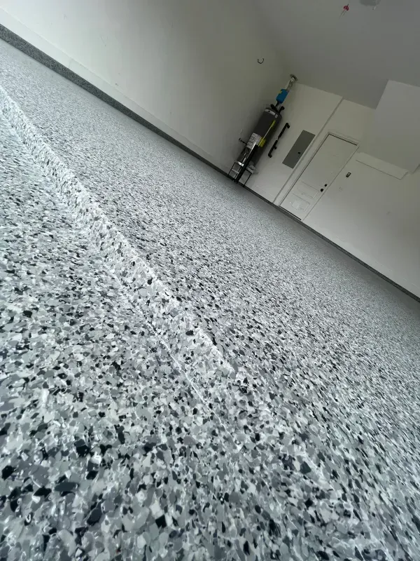 Empty speckled floor in a bright, mostly empty room with cabinets along the wall