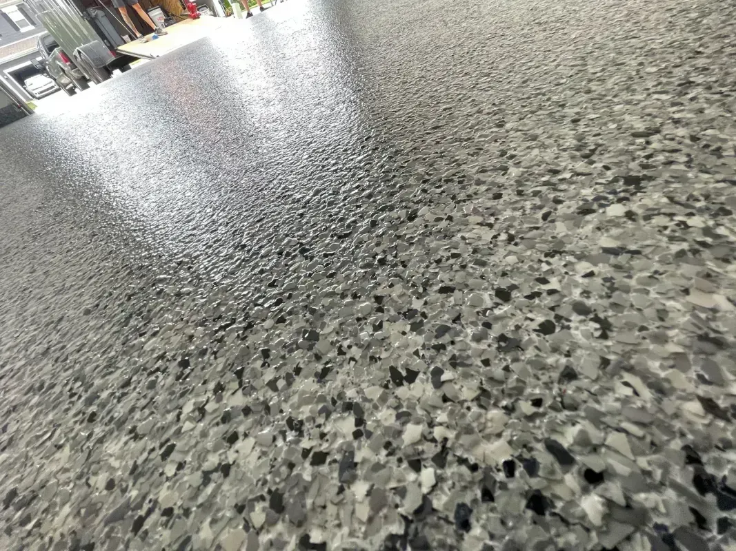 Close-up of a speckled gray granite floor with reflections from overhead lights