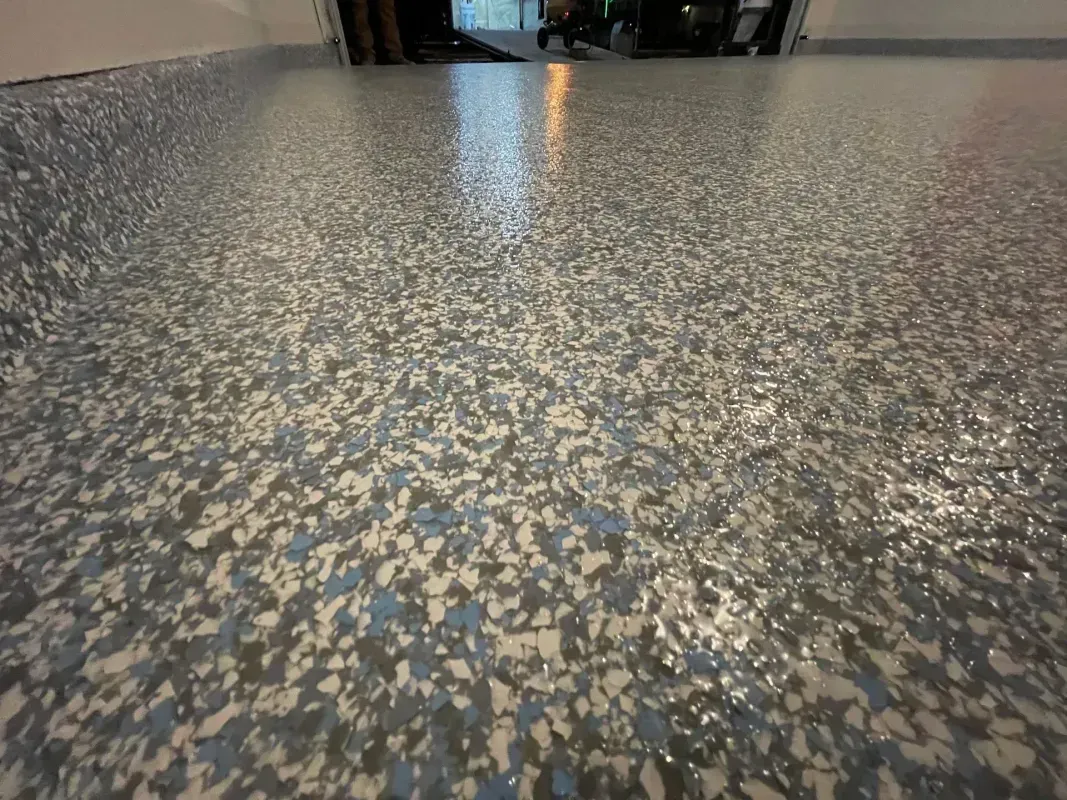 Speckled terrazzo floor in a hallway, viewed from a low angle, with distant doorway light.