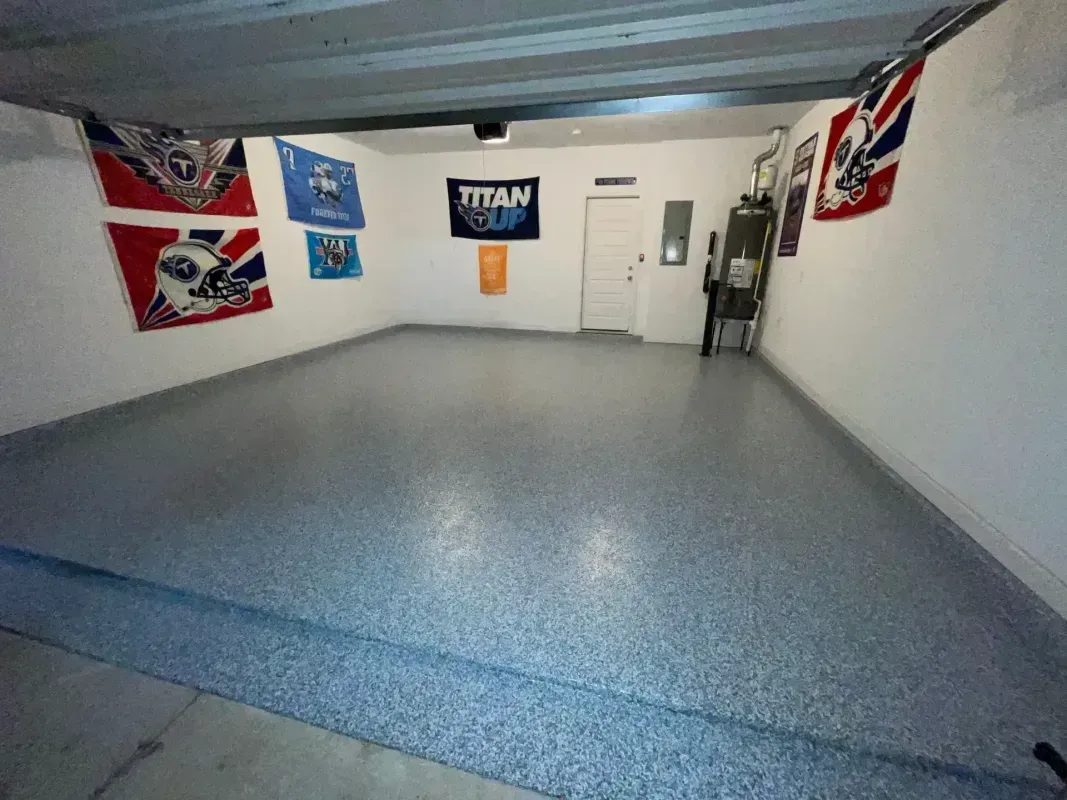 Empty garage with gray epoxy floor, white walls, and British-themed flags and signs hanging on the walls