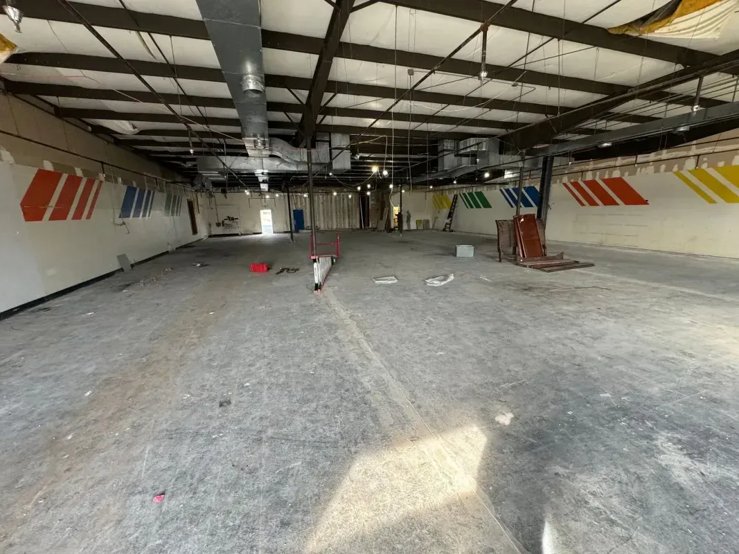 Empty warehouse interior with concrete floor, exposed beams, and red-and-white wall stripes