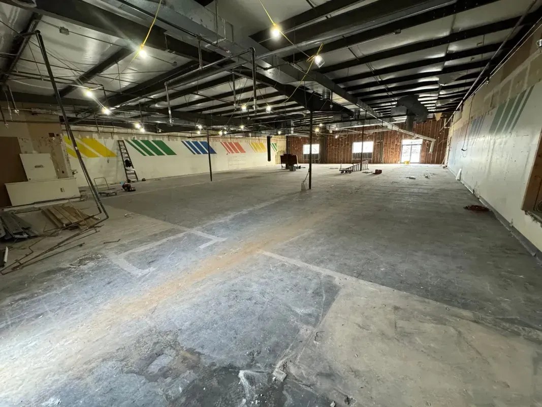 Empty industrial interior with exposed ceiling, concrete floor, and colorful wall panels