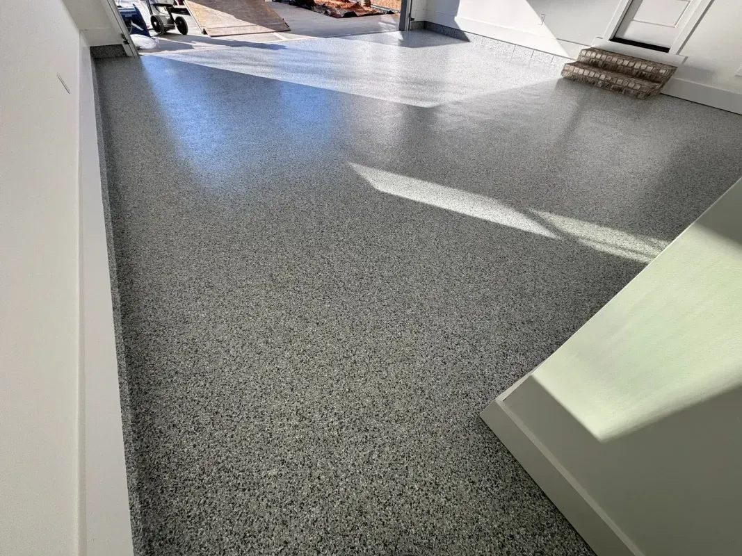 Sunlit gray speckled carpet in a modern room with white walls and doorways