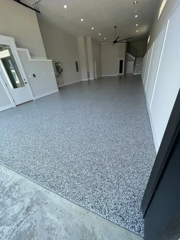 Empty modern garage interior with speckled gray floor and white walls