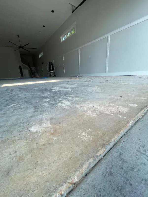 Empty concrete-floored room with unfinished walls and a large open doorway.