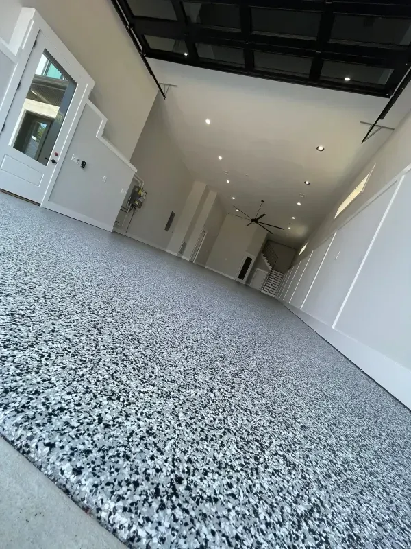 Empty modern hallway with gray speckled floor, white walls, and skylit ceiling