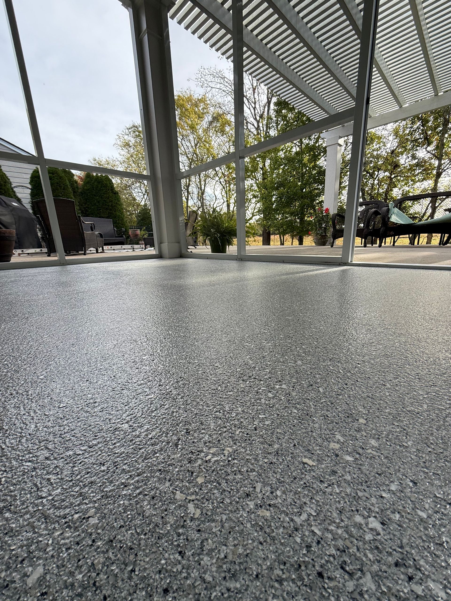Low-angle view of a textured concrete floor beneath a metal pergola in a park