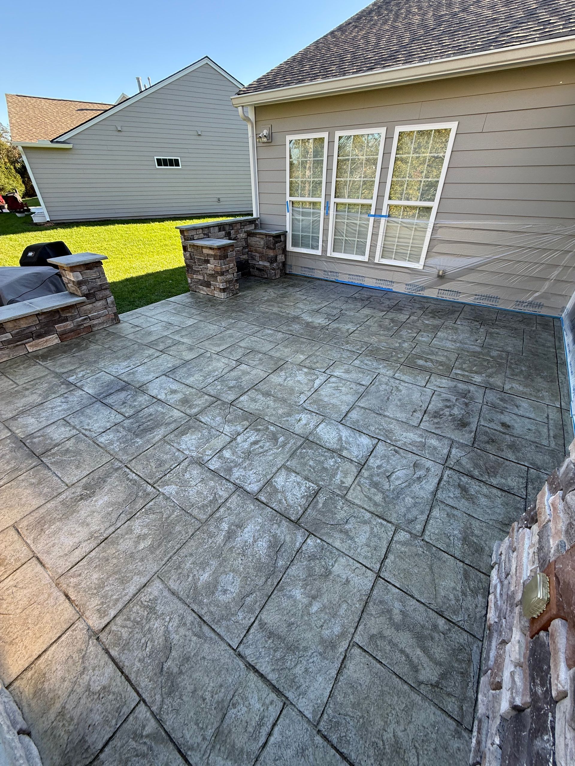 Stone patio beside a house with sliding glass doors and a small outdoor seating area
