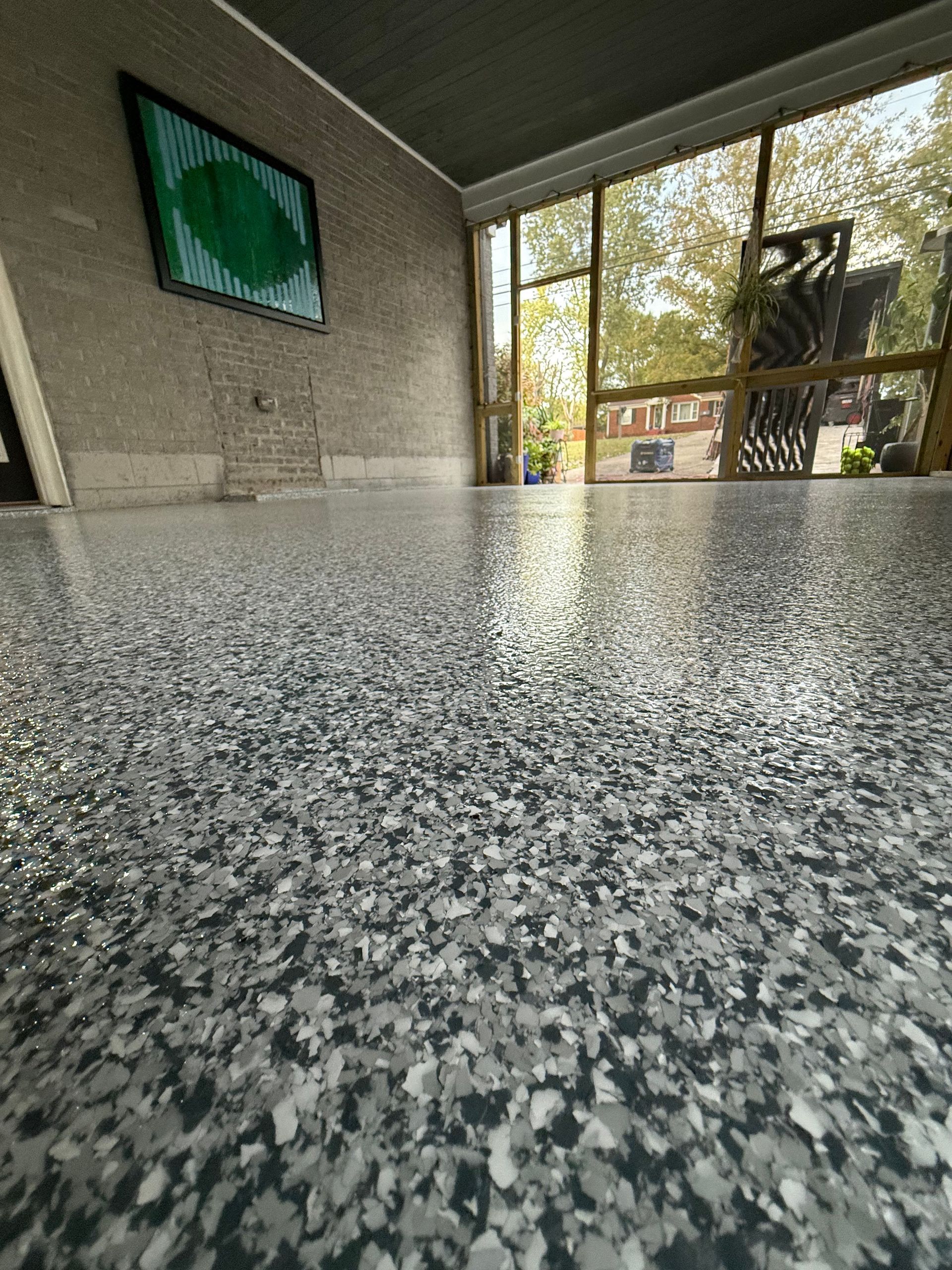 Granite countertop in a lobby or café with a wall-mounted TV and large windows overlooking trees.