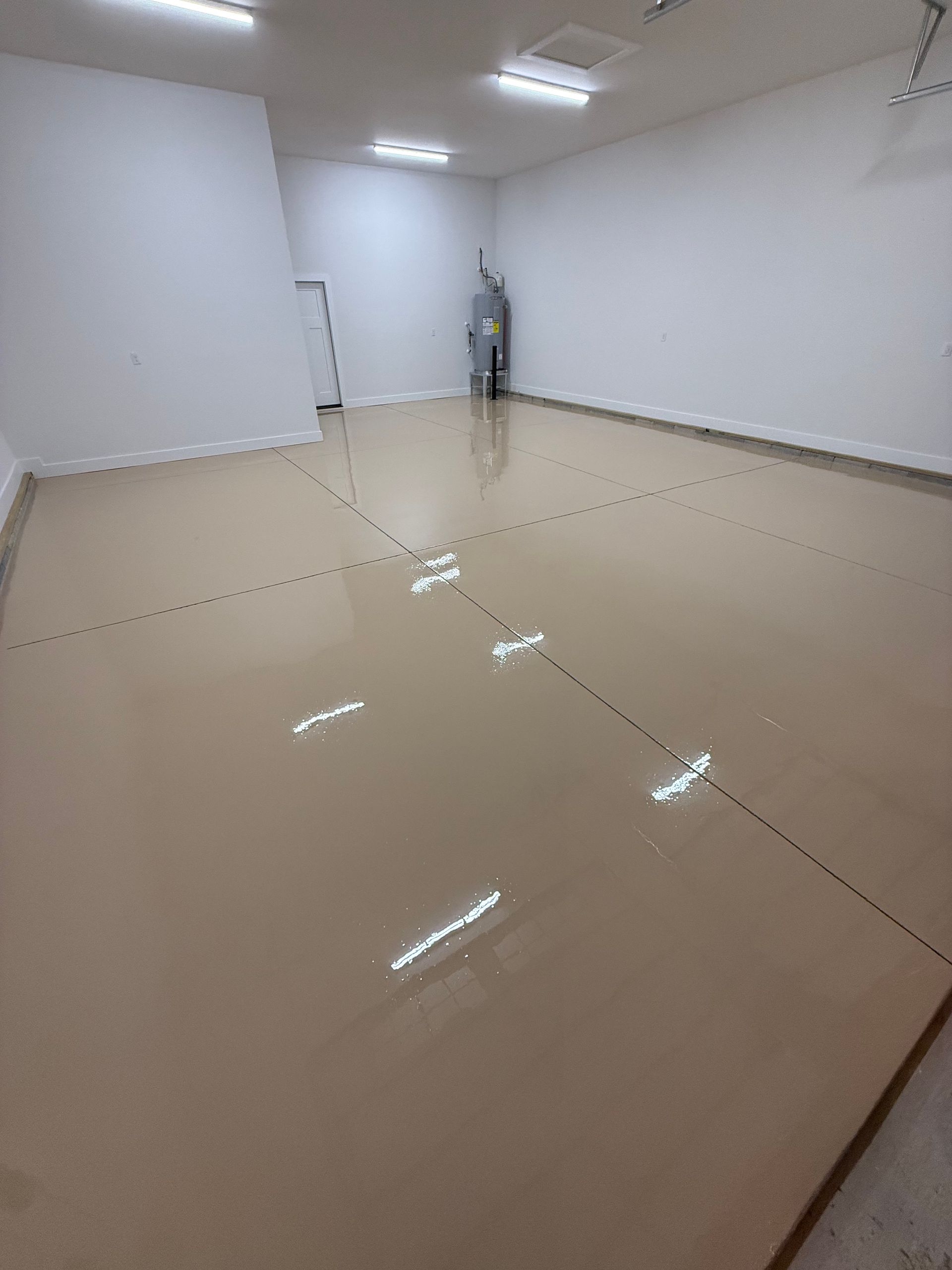 Empty beige room with white walls and glossy floor, lit by overhead fluorescent lights.