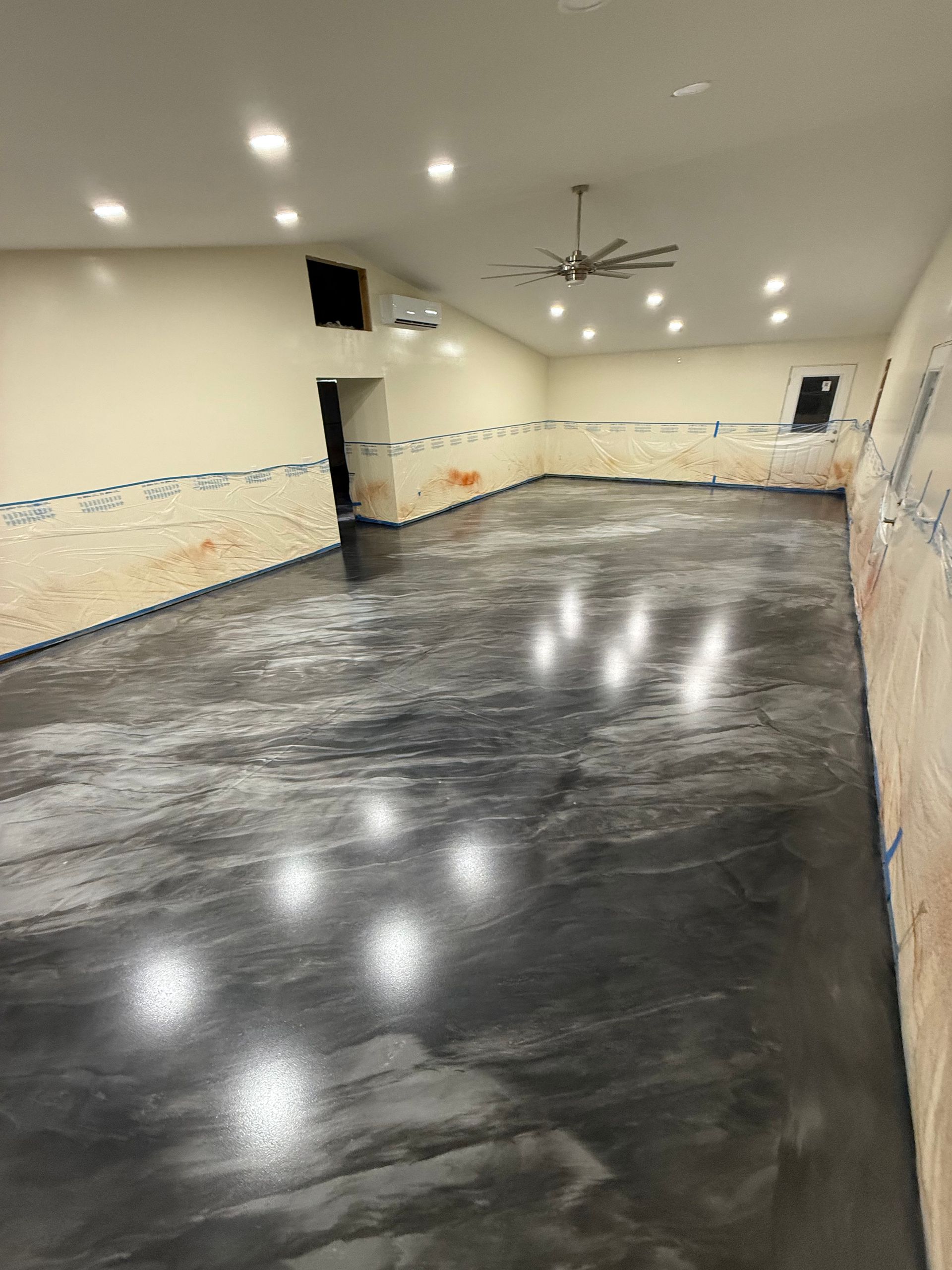 Empty room with glossy dark floor, cream walls, recessed lights, and a ceiling fan.