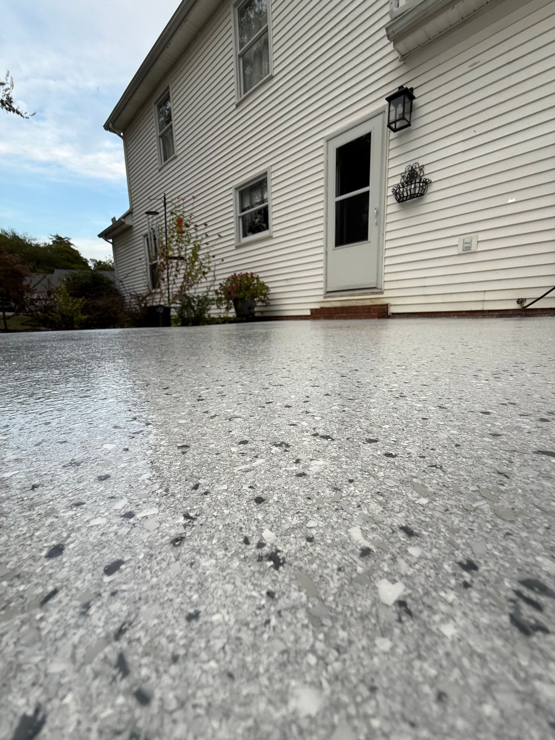 Low-angle view of a white house exterior and wet patio after rain